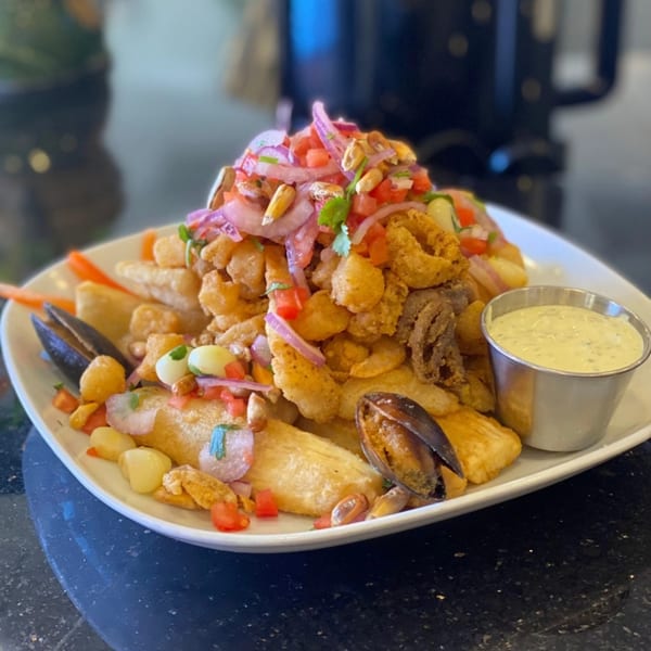 Peruvian Jalea Mixta, a platter of fried seafood, yuca, and mussels, topped with salsa criolla.